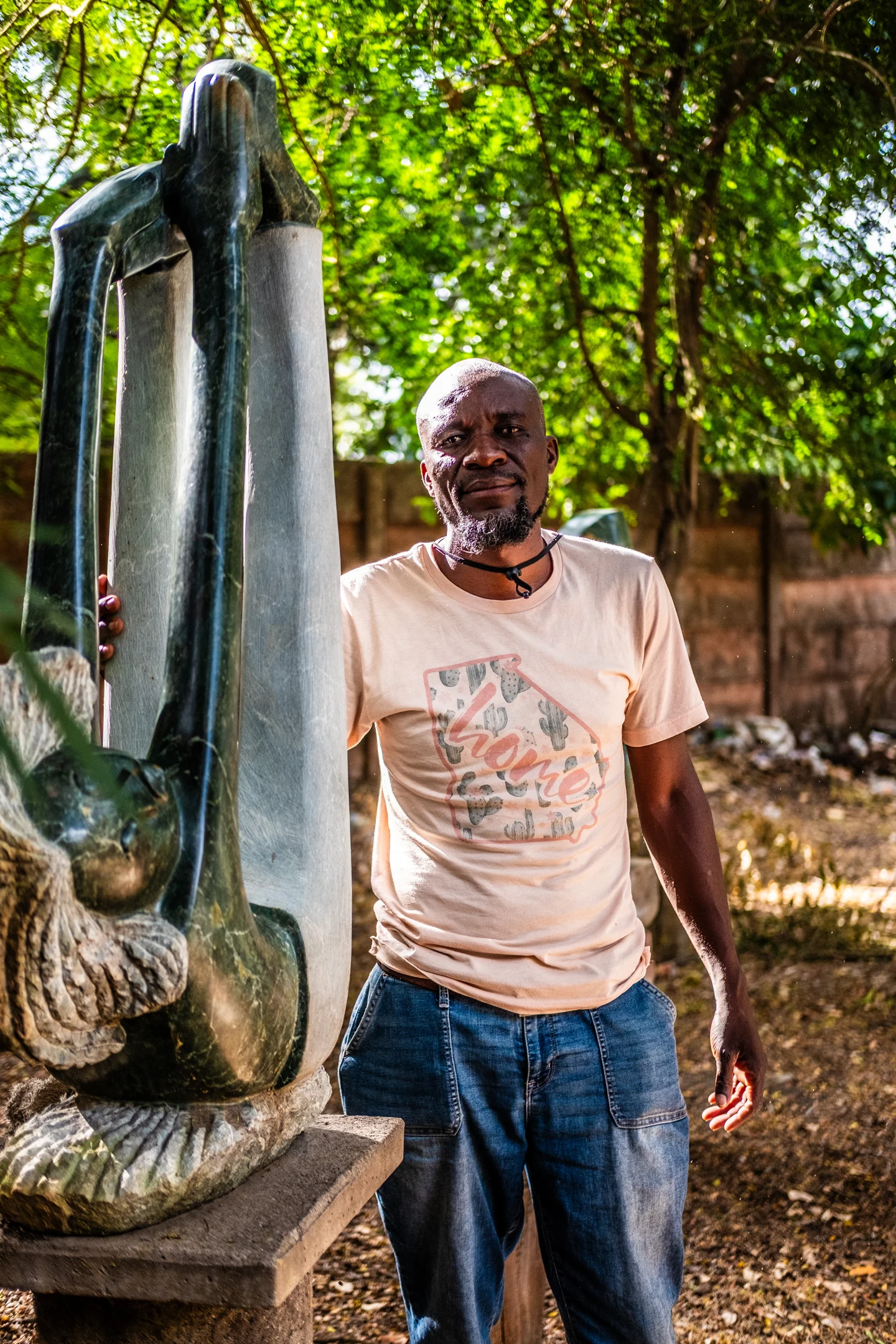 A sculptor standing beside a tall stone sculpture