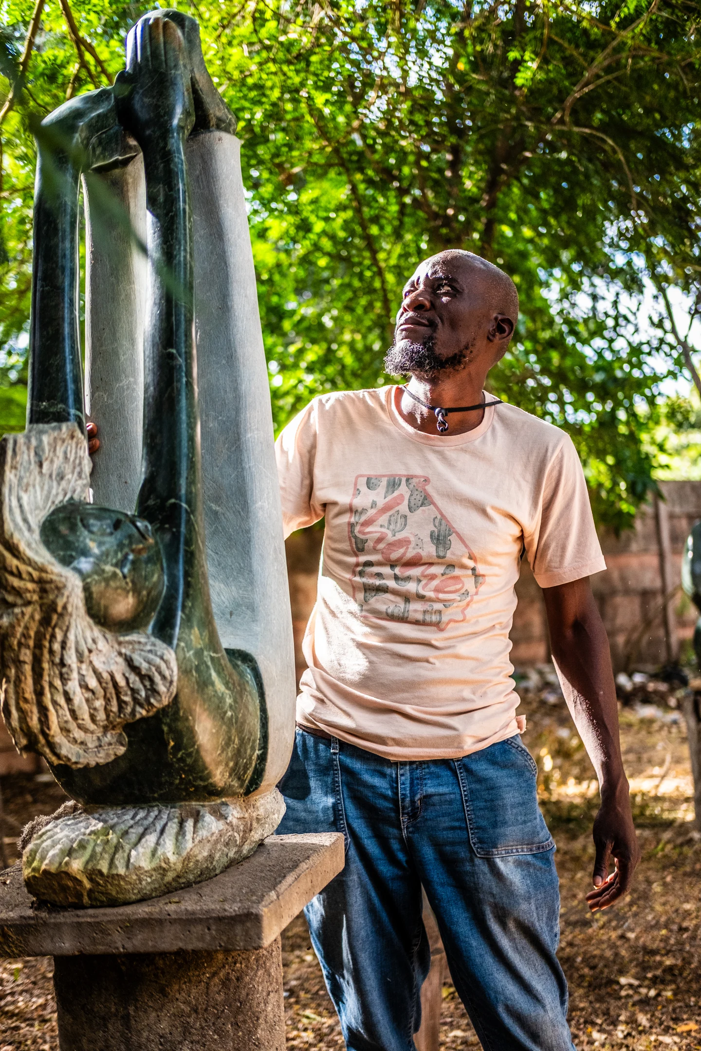 A sculptor looking up at a tall stone sculpture